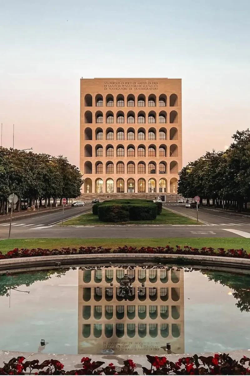 Vue et reflet du Colisée carré dans un bassin d'eau au coucher du soleil