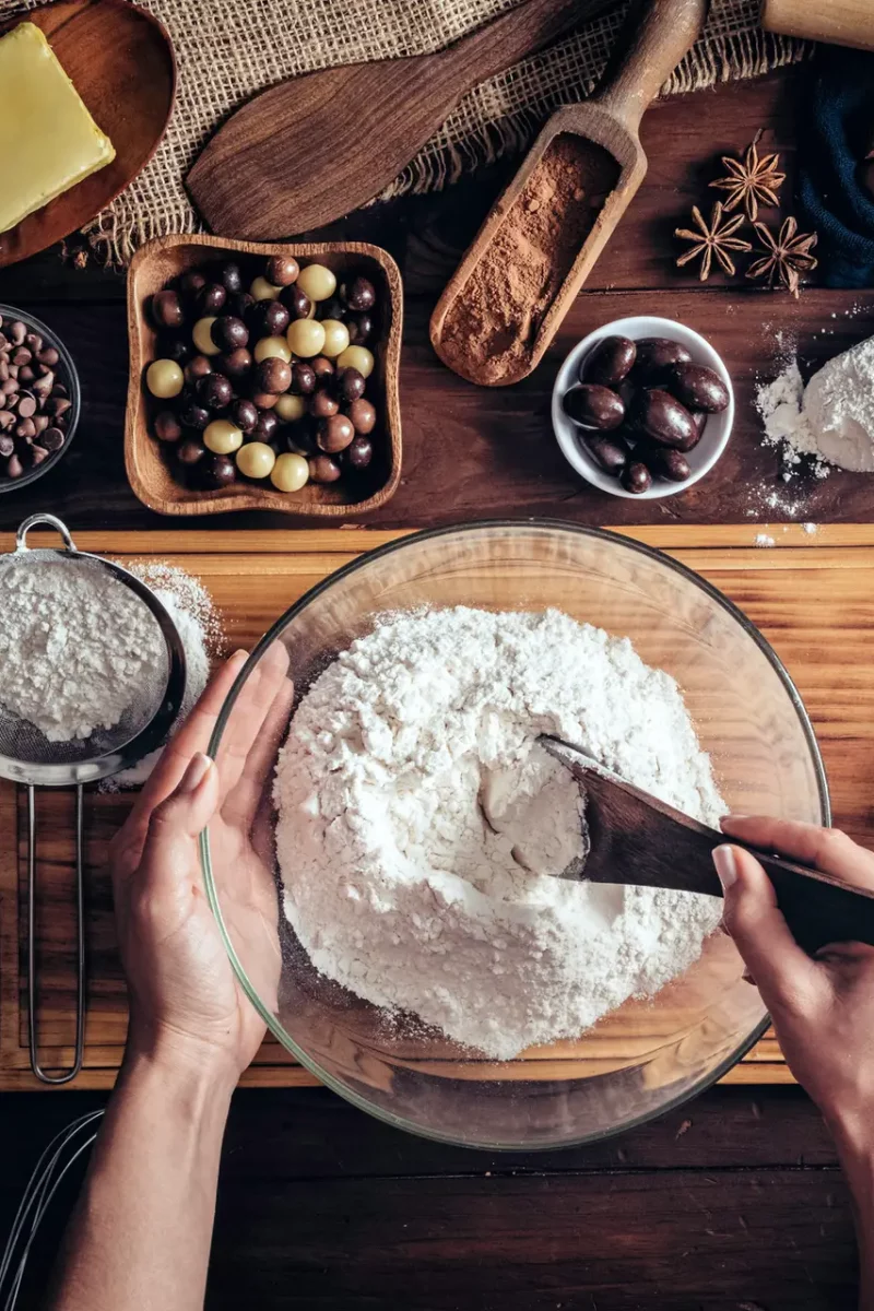 Woman hands making chocolate mousse and cookies on a wooden table in a rustic kitchen