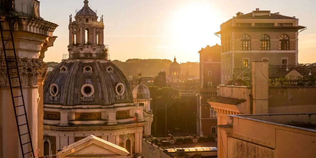 Rome, Italy, October 08 -- A view of the sunset light between the iconic rooftops of Piazza Venezia, in the heart of the eternal city, with the dome of the church of Santa Maria di Loreto and a portion of Palazzo Venezia. Image in High Definition format.